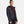 Black rain jacket by Under Armour with a hood, front snap-button closure, and white chest logo, worn over a red top.