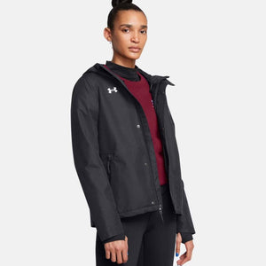 Black rain jacket by Under Armour with a hood, front snap-button closure, and white chest logo, worn over a red top.
