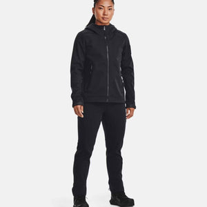 Black tactical softshell jacket by Under Armour, hooded with a full zipper, worn by a woman with black pants.