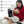 Black far infrared heating therapy pad by UTK Technology worn on a woman's arm, with a digital controller on the floor.