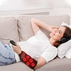 Black heating therapy pad by UTK Technology with red glowing elements, wrapped on a woman's forearm while she relaxes on a couch.