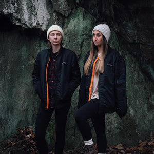Black bomber jacket by Venture Heat, featuring a bright orange zipper lining, worn by two women outdoors.