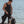 Black wrist remote controller by Venture Heat, worn on a man's left wrist in a black wetsuit by the ocean.