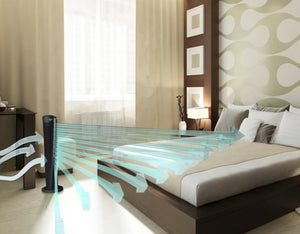 Black 29-inch Tower Circulator by Vornado, shown in a bedroom with blue air streams flowing over a bed.