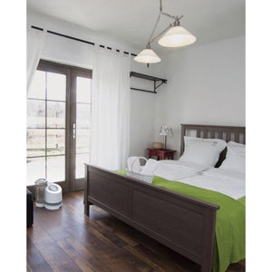 White evaporative humidifier by Vornado with a round top grille, sitting on a dark wood floor.