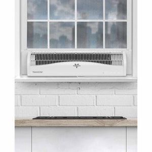 White transom window air circulator by Vornado, installed in a window above a white brick wall.