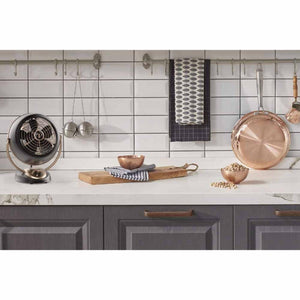 Gunmetal VFan Alchemy fan by Vornado, a vintage-style desk fan with bronze-gold accents, on a kitchen counter.