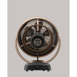 Vintage style fan in gunmetal by Vornado with a round metal cage and black base.