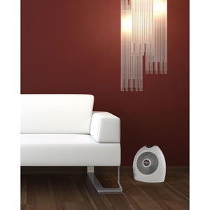 White oval whole room heater by Vornado with a spiral grill, on a wooden floor beside a white sofa.