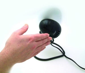 Black personal fan by Vornado, compact with "Zippi" text, a grille, and a hand reaching towards it.