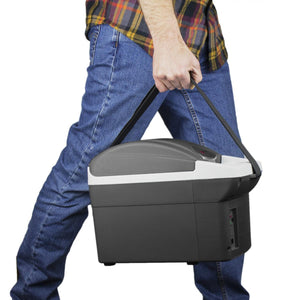 Dark gray and white Thermo-Electric Cooler/Warmer by Wagan with a black strap, carried by a person in blue jeans.