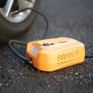 Orange tire inflator by Wagan with a black hose and light, shown on asphalt connected to a car tire.