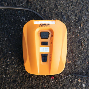 Orange digital tire inflator by Wagan, showing "37.0" on display, with black buttons and hose, on asphalt.
