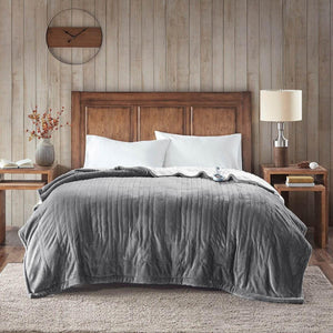 Grey ribbed plush to Berber heated blanket by Woolrich, draped over a bed with white pillows in a rustic bedroom.