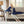 Navy blue heated plush to Berber throw by Woolrich, draped over a woman relaxing on a sofa, holding its controller.
