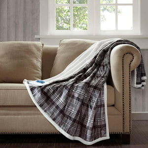 Brown and white plaid oversized heated throw by Woolrich, featuring a mink front and white berber reverse, draped on a sofa.