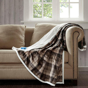 Brown plaid heated throw by Woolrich with white sherpa lining draped over a beige couch.