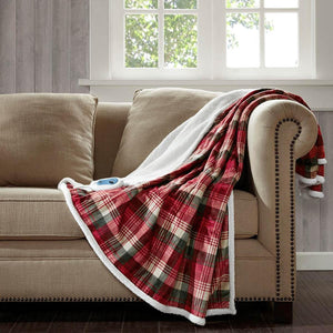 Red plaid heated throw by Woolrich with soft white berber lining and remote controller, draped over a sofa.